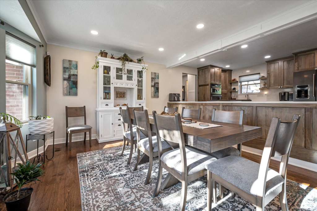 Dining space featuring healthy amount of natural light, dark wood-style floors, baseboards, recessed lighting, and ornamental molding