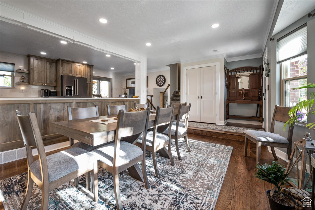 Dining area featuring crown molding, plenty of natural light, dark wood-type flooring, recessed lighting, and stairway
