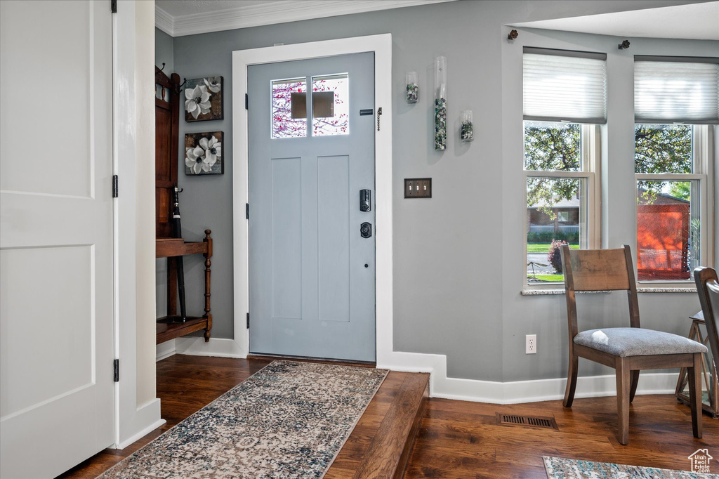 Entryway with dark wood-style floors, baseboards, and crown molding