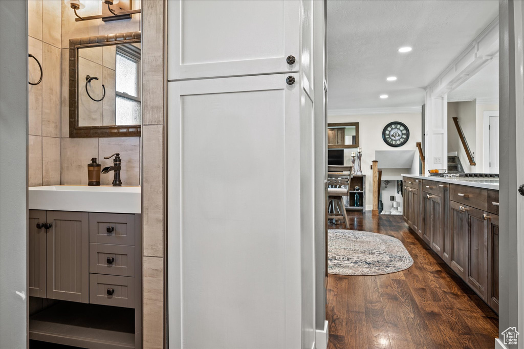 Bathroom with ornamental molding, vanity, wood finished floors, and recessed lighting