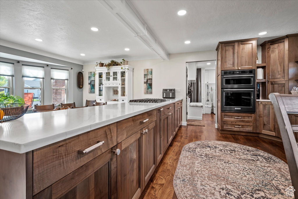Kitchen with light countertops, recessed lighting, brown cabinets, dark wood finished floors, and a peninsula