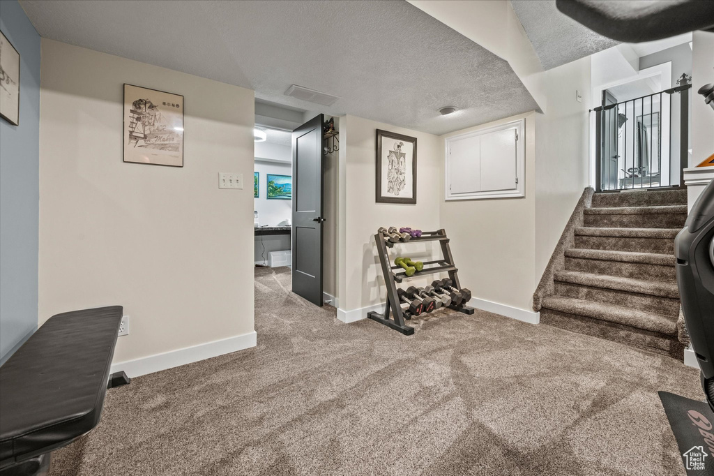 Basement with baseboards, carpet floors, stairway, and a textured ceiling