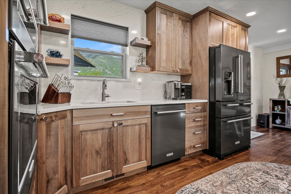 Kitchen featuring black refrigerator with ice dispenser, open shelves, dishwasher, dark wood finished floors, and a sink