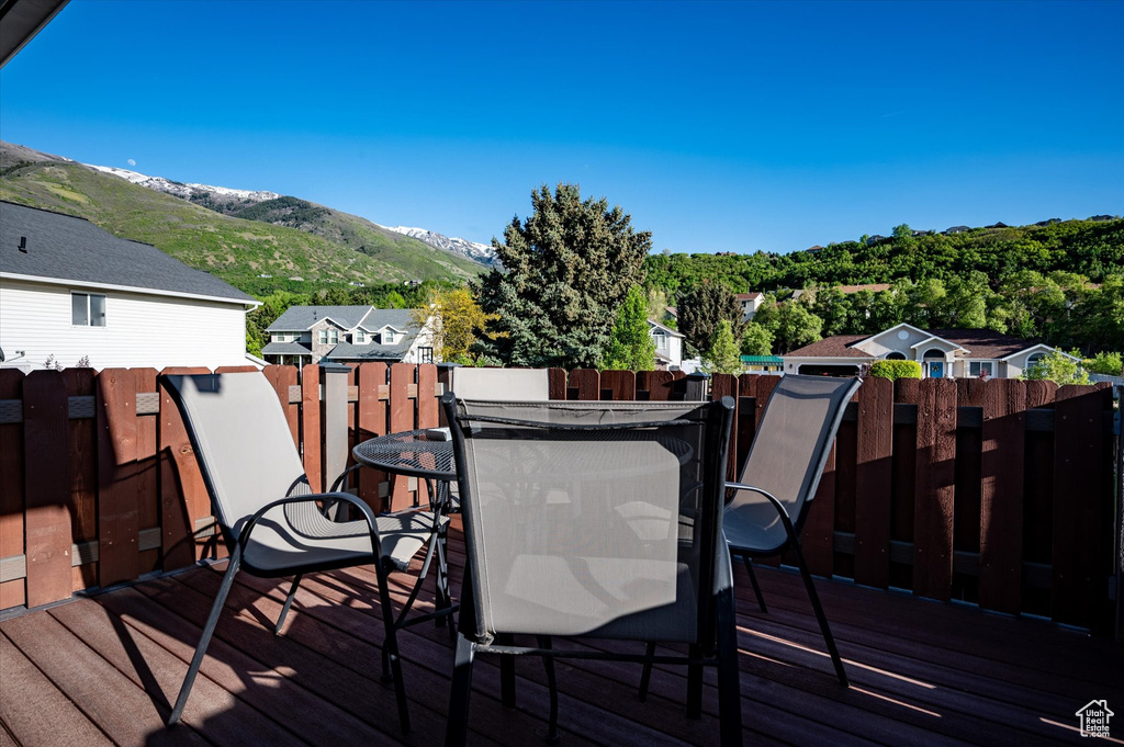 Deck with outdoor dining space, a mountain view, and fence