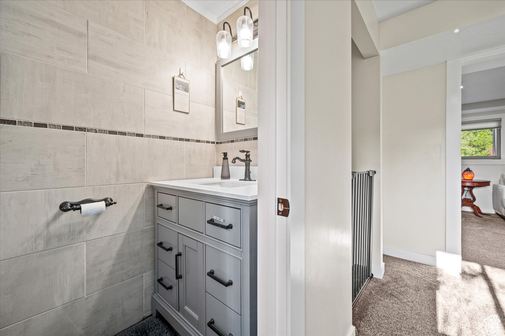 Bathroom featuring tile walls, vanity, and crown molding