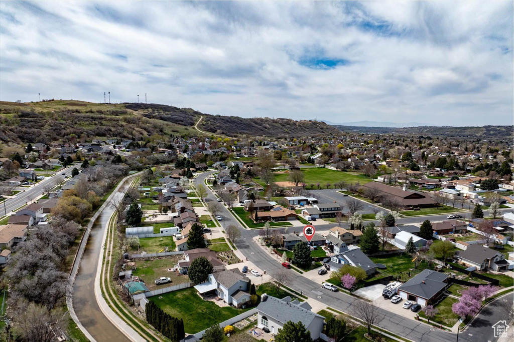 Aerial view of property and surrounding area featuring nearby suburban area and a mountainous background