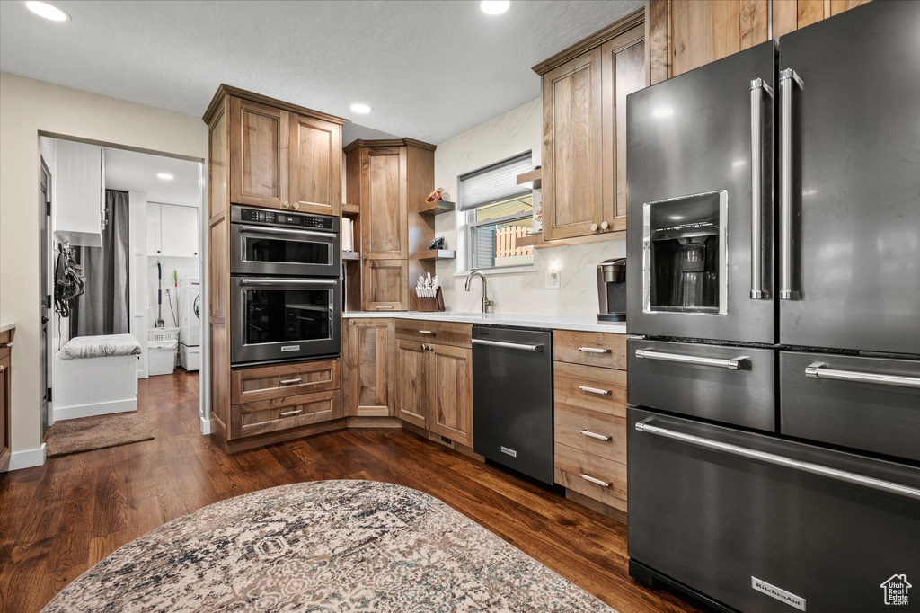 Kitchen featuring stainless steel appliances, dark wood finished floors, recessed lighting, light countertops, and brown cabinets