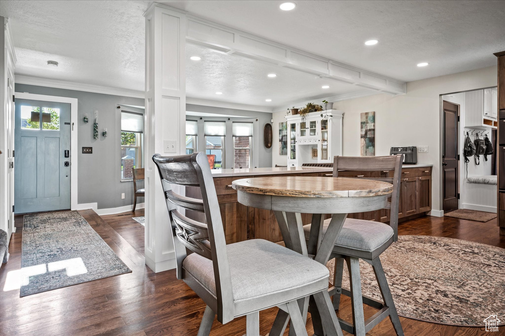 Dining space with recessed lighting, ornamental molding, dark wood finished floors, baseboards, and a textured ceiling