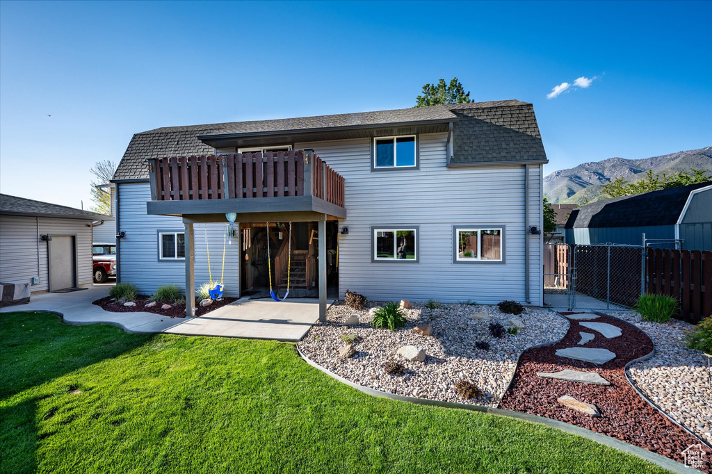 Back of property featuring a shingled roof, a mountain view, and a patio area