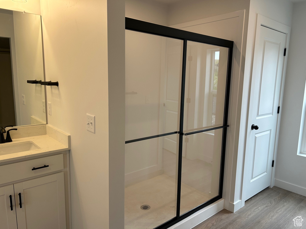Bathroom with wood finished floors, a stall shower, vanity, and baseboards