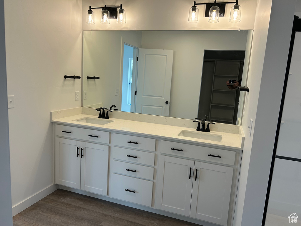 Full bathroom with wood finished floors, double vanity, and baseboards
