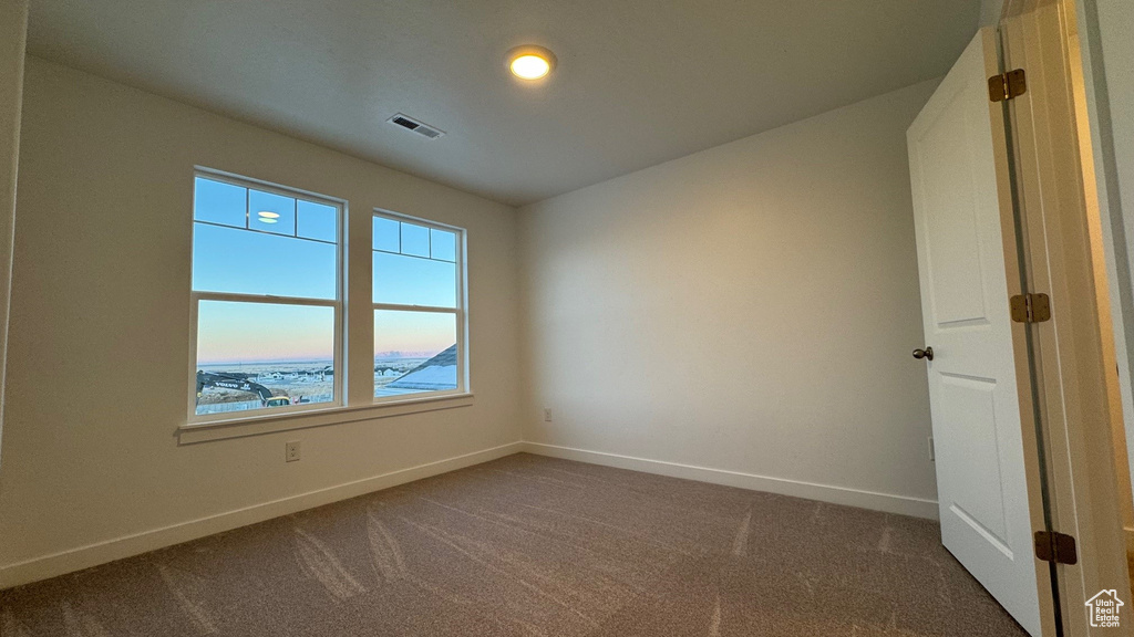 Unfurnished room with dark colored carpet and baseboards