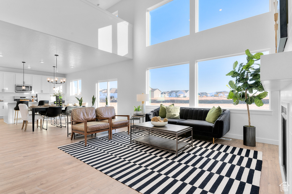 Living room with light wood-type flooring, a chandelier, and recessed lighting