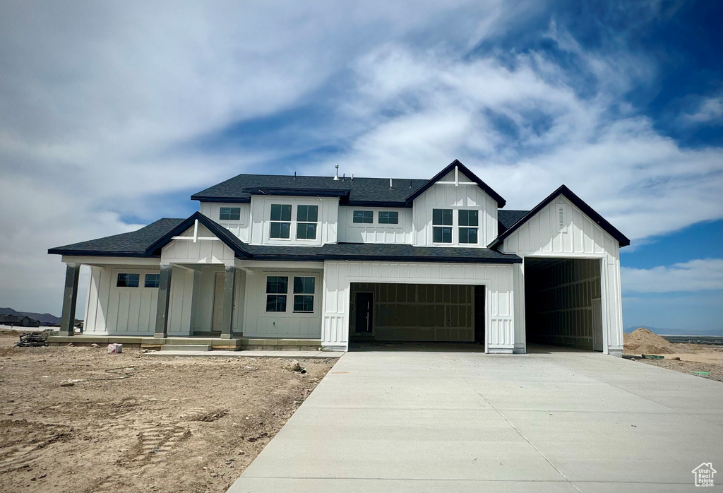 Modern inspired farmhouse featuring board and batten siding, concrete driveway, covered porch, a garage, and a shingled roof