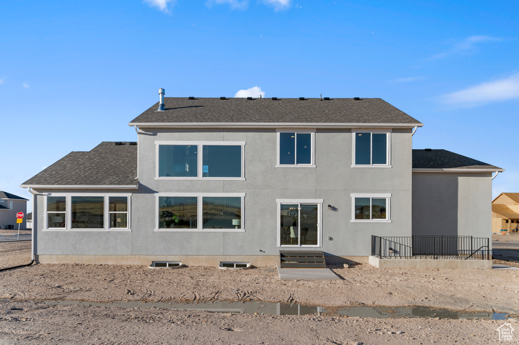 Back of property featuring roof with shingles and stucco siding