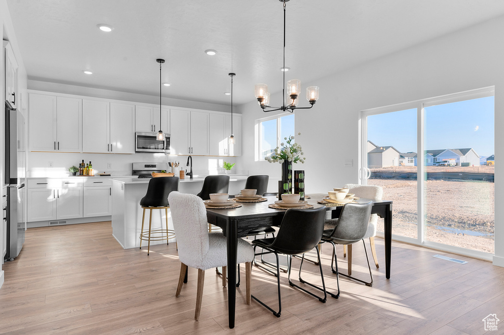Dining room featuring light wood-style floors, healthy amount of natural light, a chandelier, and recessed lighting