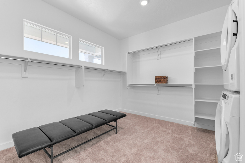 Spacious closet featuring stacked washing machine and dryer and carpet flooring