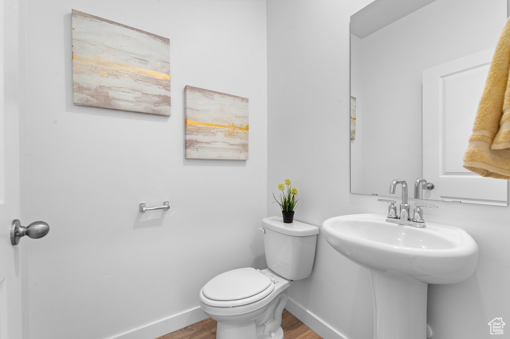 Bathroom with baseboards, wood finished floors, and toilet