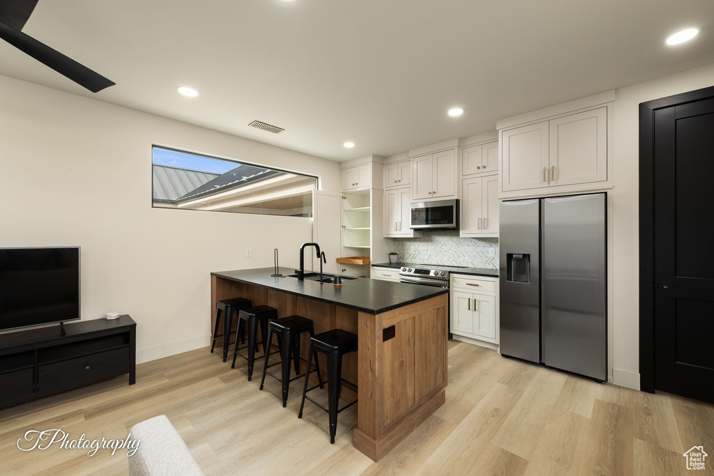 Kitchen with appliances with stainless steel finishes, a sink, a breakfast bar area, a peninsula, and dark countertops