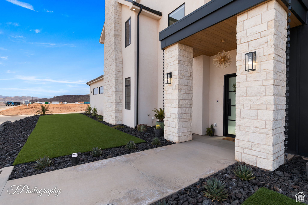 View of exterior entry featuring stucco siding, stone siding, and a mountain view