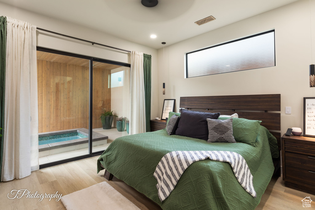Bedroom with access to exterior, wood finished floors, multiple windows, and recessed lighting