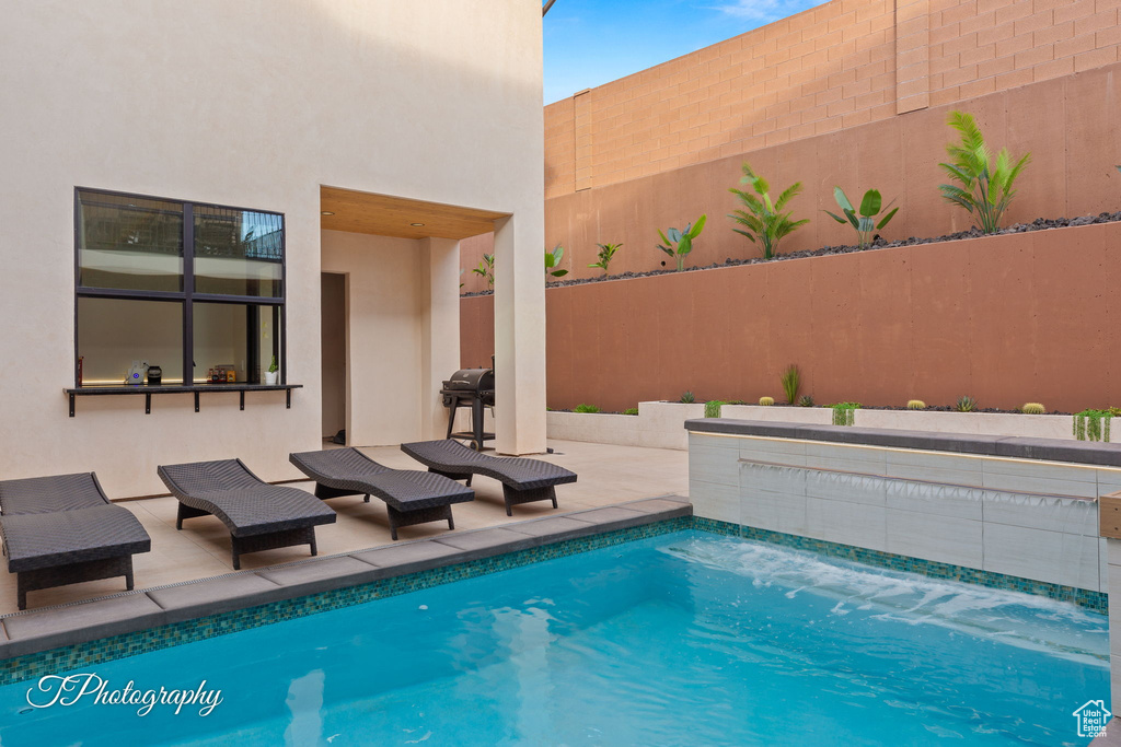 Outdoor pool featuring fence, a patio, and a grill