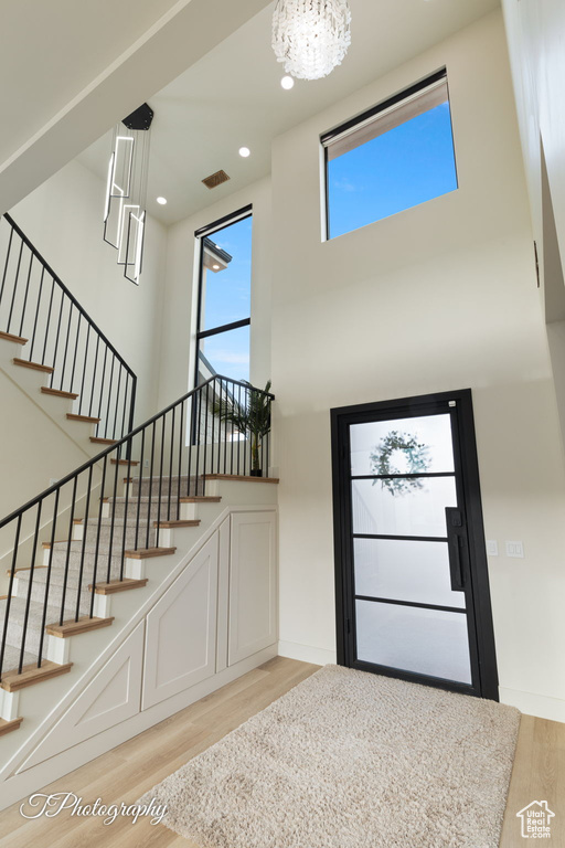 Entryway with light wood-style floors, a high ceiling, a chandelier, stairs, and recessed lighting