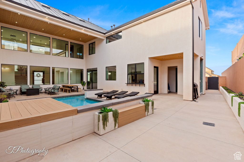 Rear view of house featuring outdoor lounge area, stucco siding, a patio, and a fenced backyard