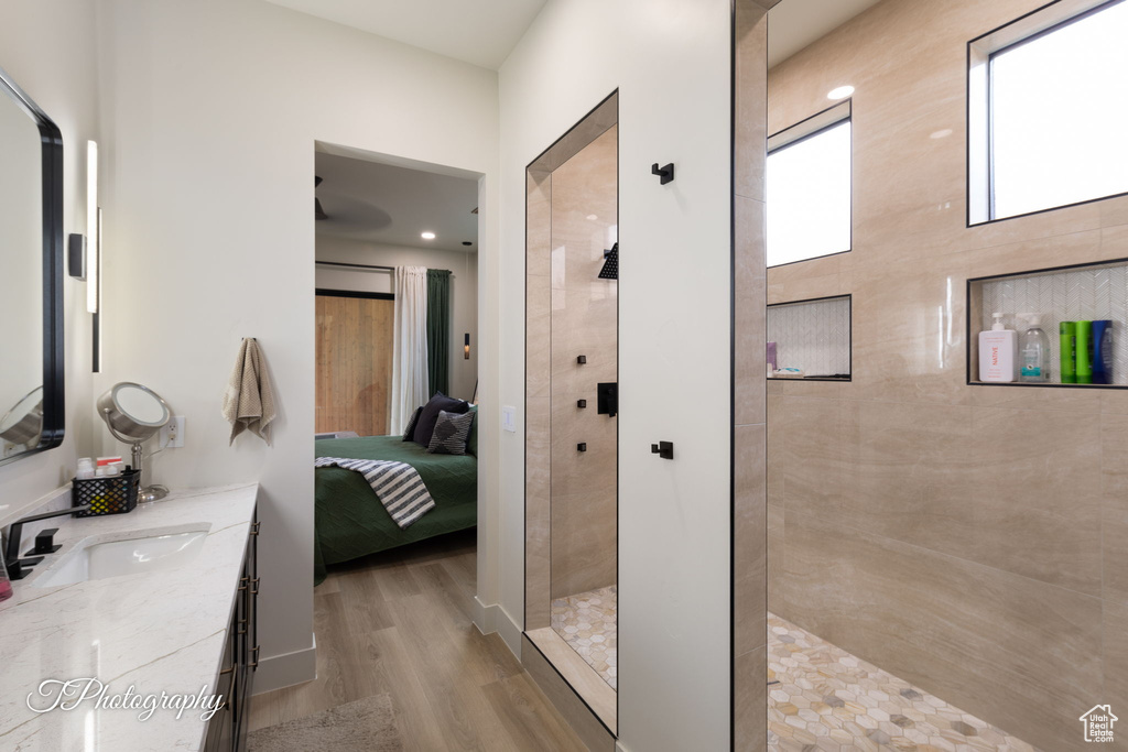 Bathroom with ensuite bathroom, wood finished floors, a walk in shower, and vanity
