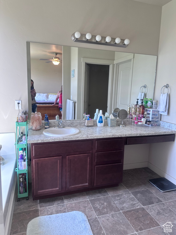 Ensuite bathroom featuring vanity, ceiling fan, and stone finish floors