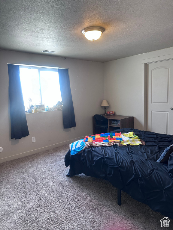 Bedroom with a textured ceiling, carpet, and baseboards