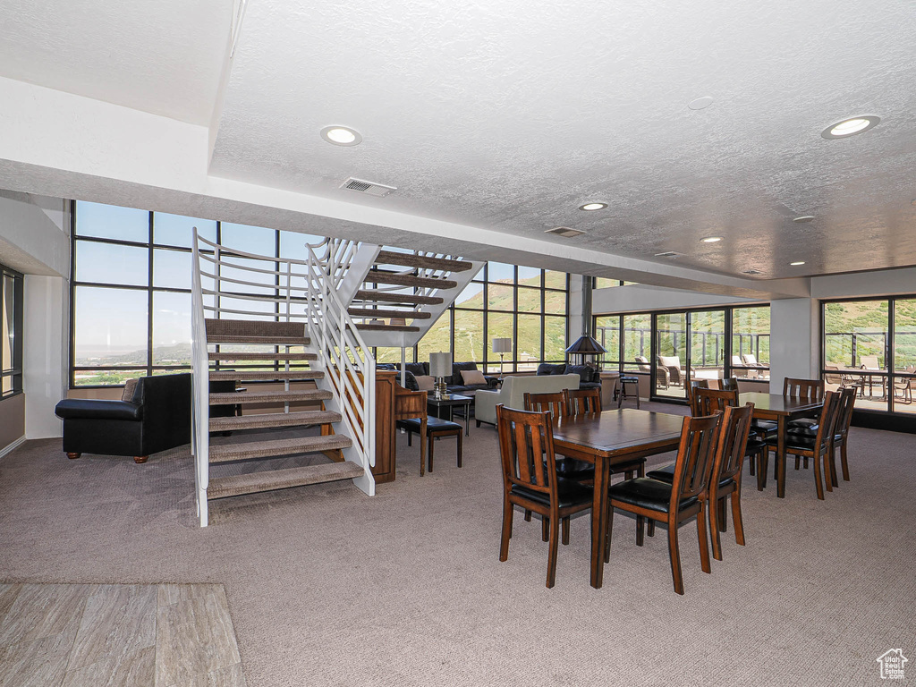 Dining area featuring carpet, a textured ceiling, recessed lighting, and stairway
