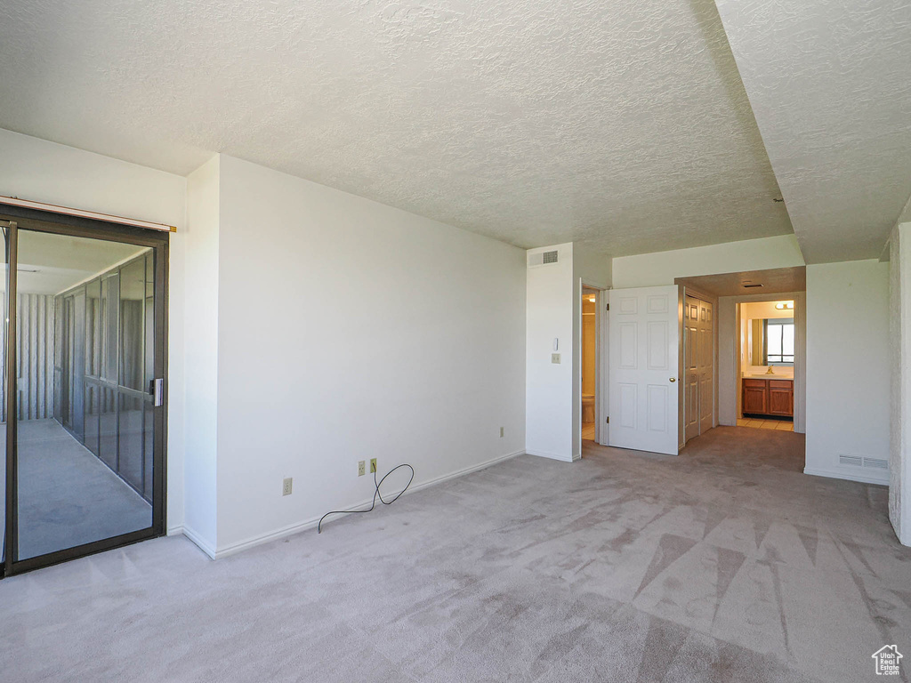 Spare room with light carpet, a textured ceiling, and baseboards