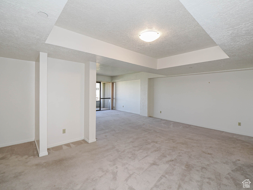 Spare room featuring a textured ceiling, light colored carpet, and baseboards