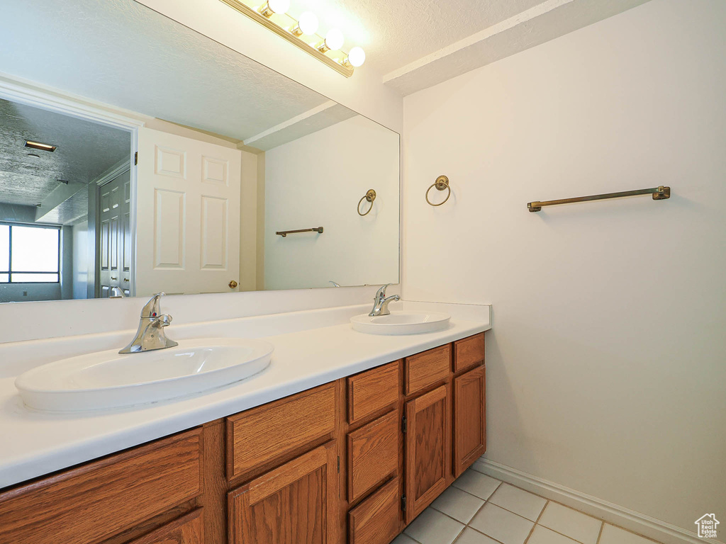 Full bath with tile patterned flooring, double vanity, and baseboards