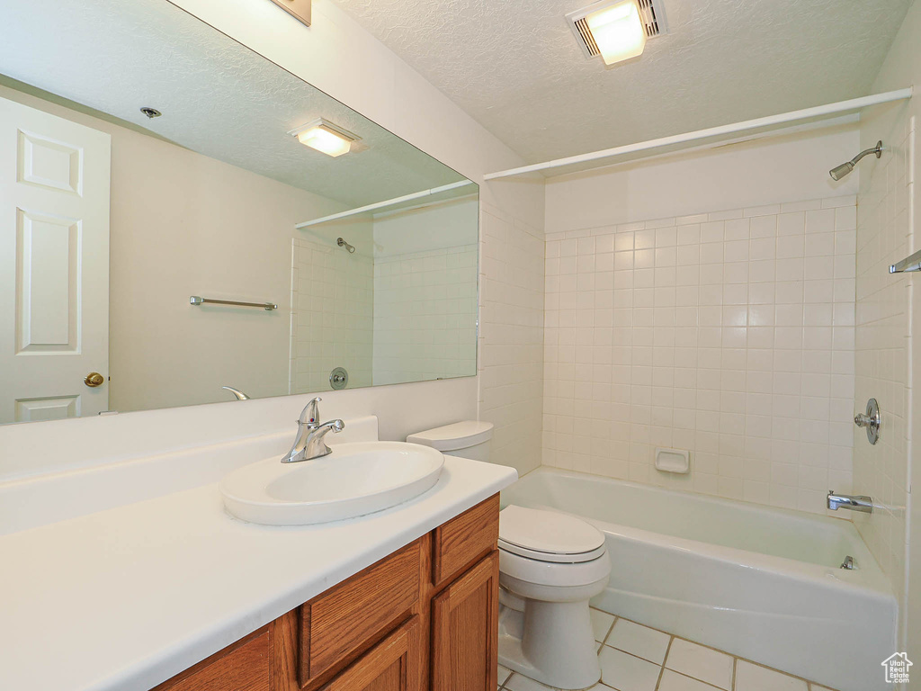 Full bath with toilet, tile patterned floors, vanity, shower / tub combination, and a textured ceiling