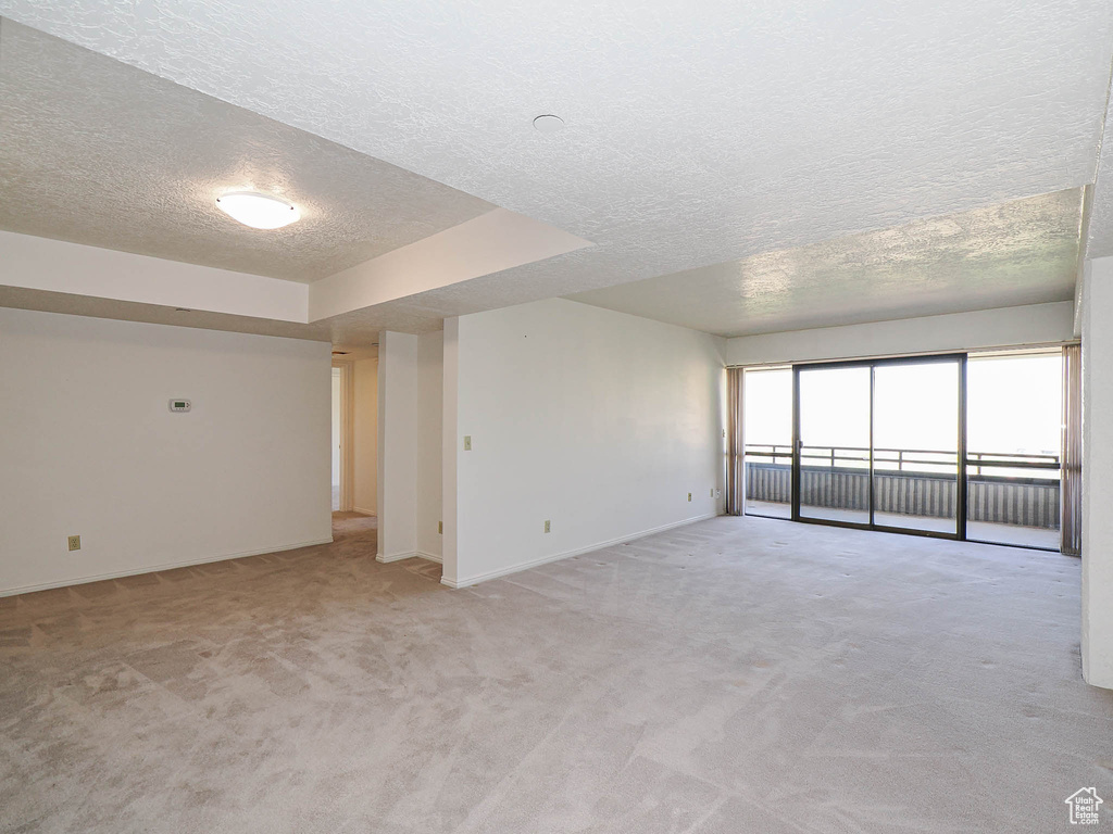 Unfurnished room featuring a textured ceiling, light colored carpet, and baseboards