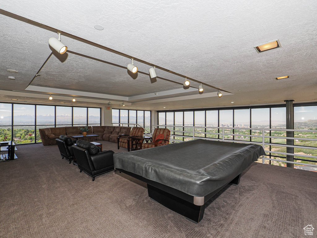 Game room featuring a textured ceiling, carpet flooring, pool table, and a wall of windows