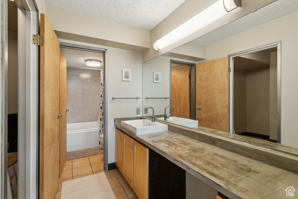 Full bath featuring tile patterned flooring, vanity, shower / tub combo, and a textured ceiling