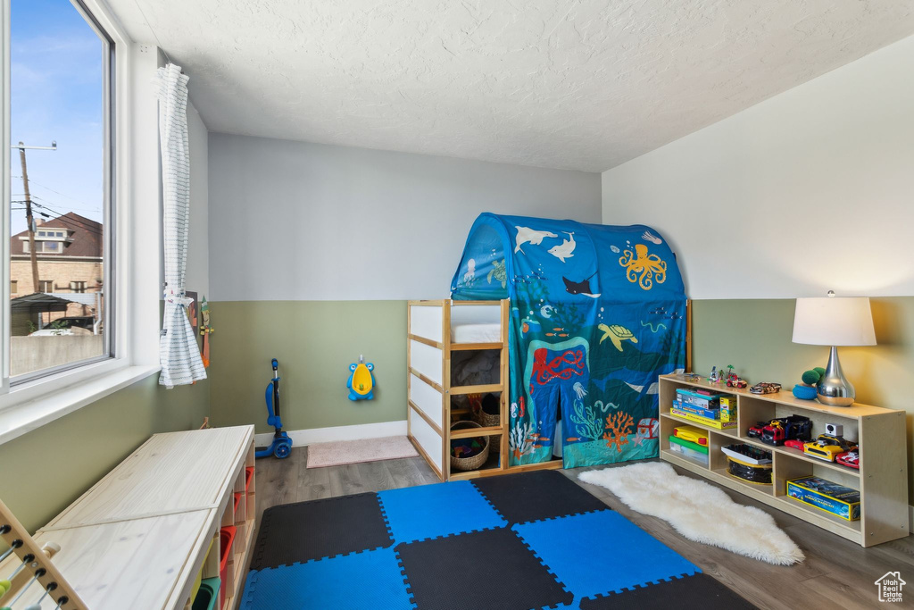 Workout area featuring wood finished floors, a textured ceiling, and baseboards