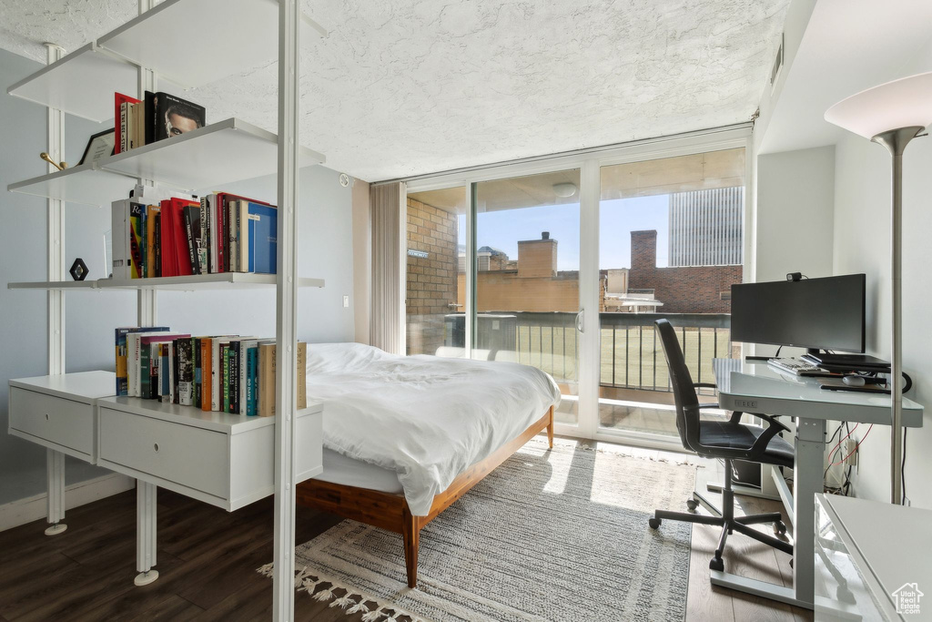 Bedroom featuring wood finished floors, access to exterior, floor to ceiling windows, and an office area