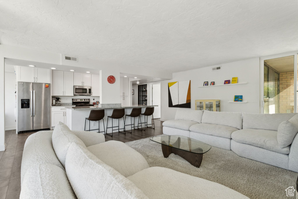 Living room with dark wood-style flooring, a textured ceiling, and recessed lighting