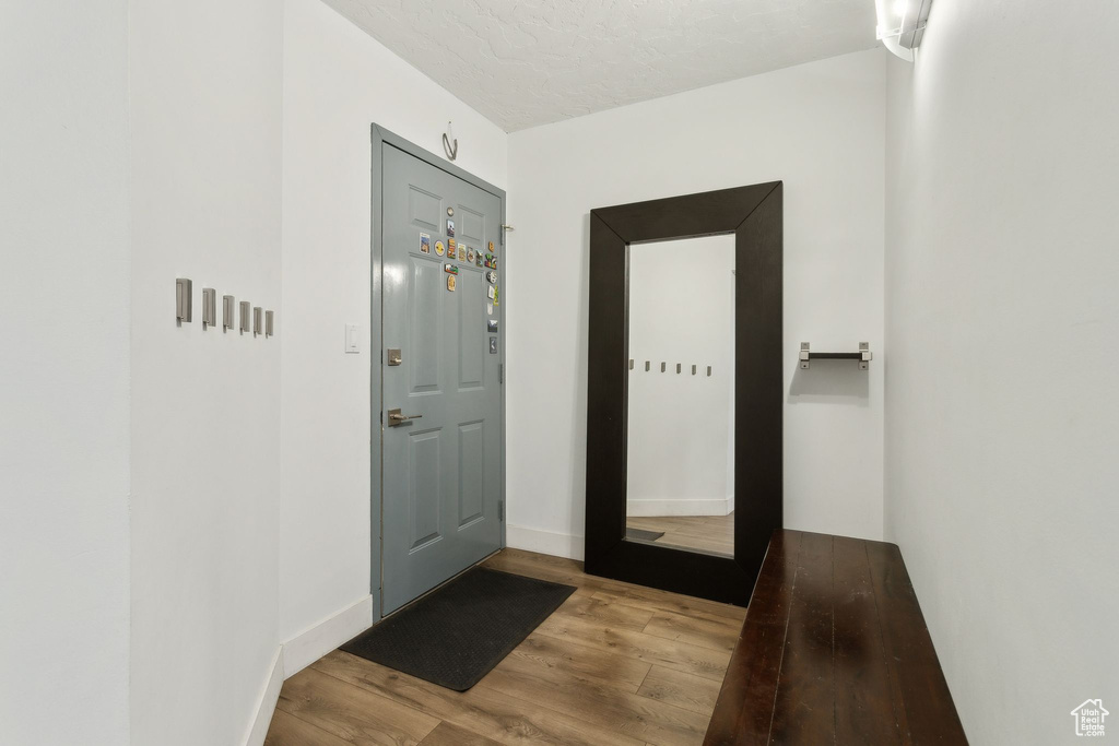 Doorway featuring wood finished floors, baseboards, and a textured ceiling