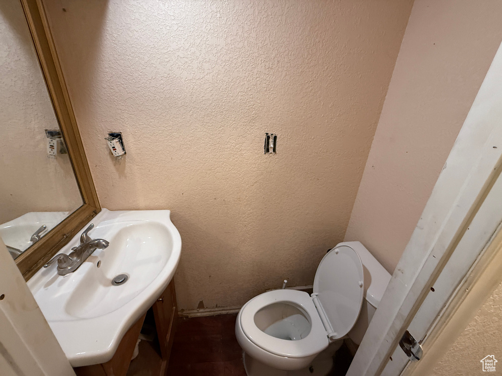 Half bathroom featuring a textured wall, vanity, and toilet
