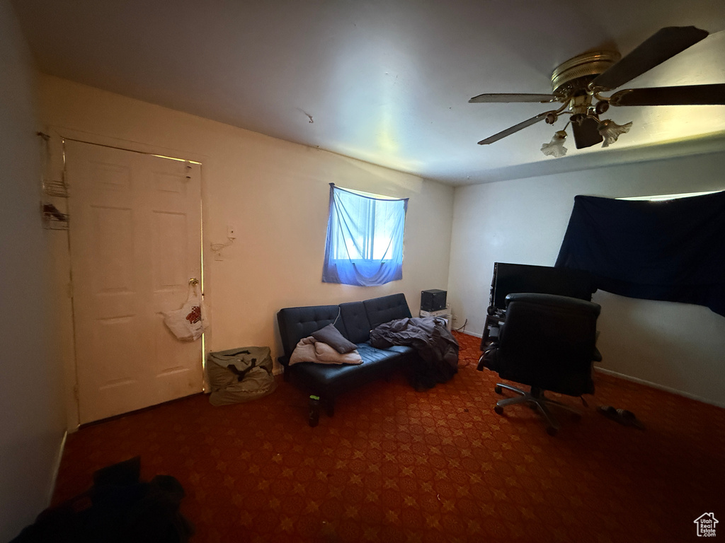 Carpeted office featuring a ceiling fan