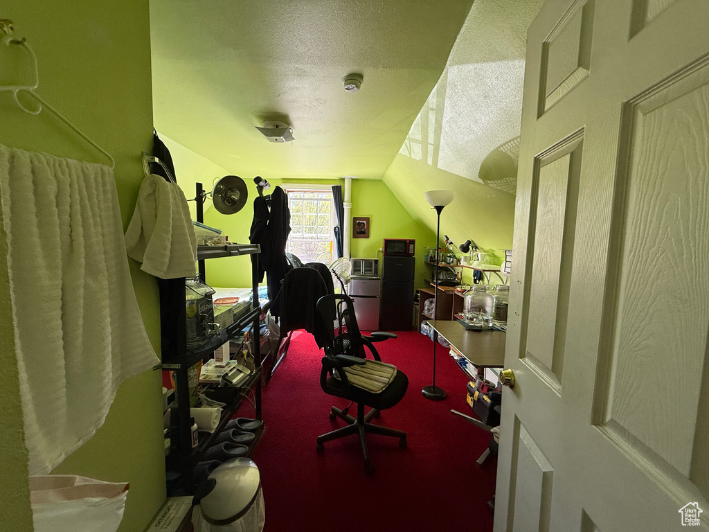 Bedroom with a textured ceiling, carpet flooring, and lofted ceiling