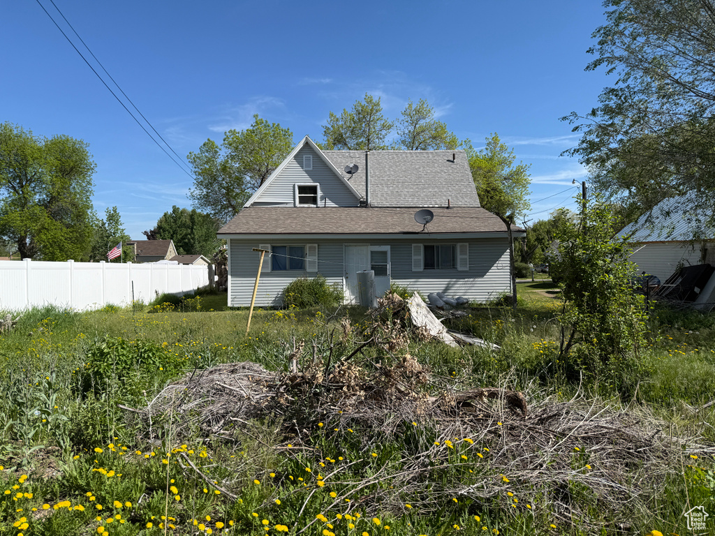Back of property featuring fence and roof with shingles