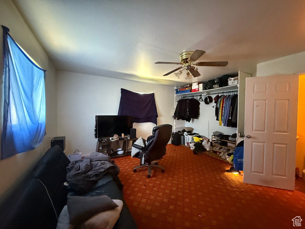 Carpeted bedroom featuring ceiling fan and a closet