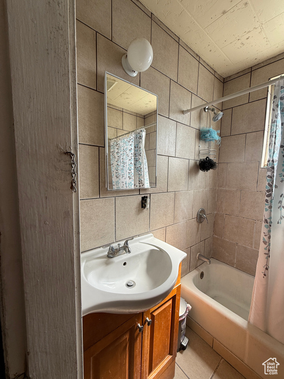 Bathroom with tile patterned floors, shower / bathtub combination with curtain, vanity, tile walls, and toilet