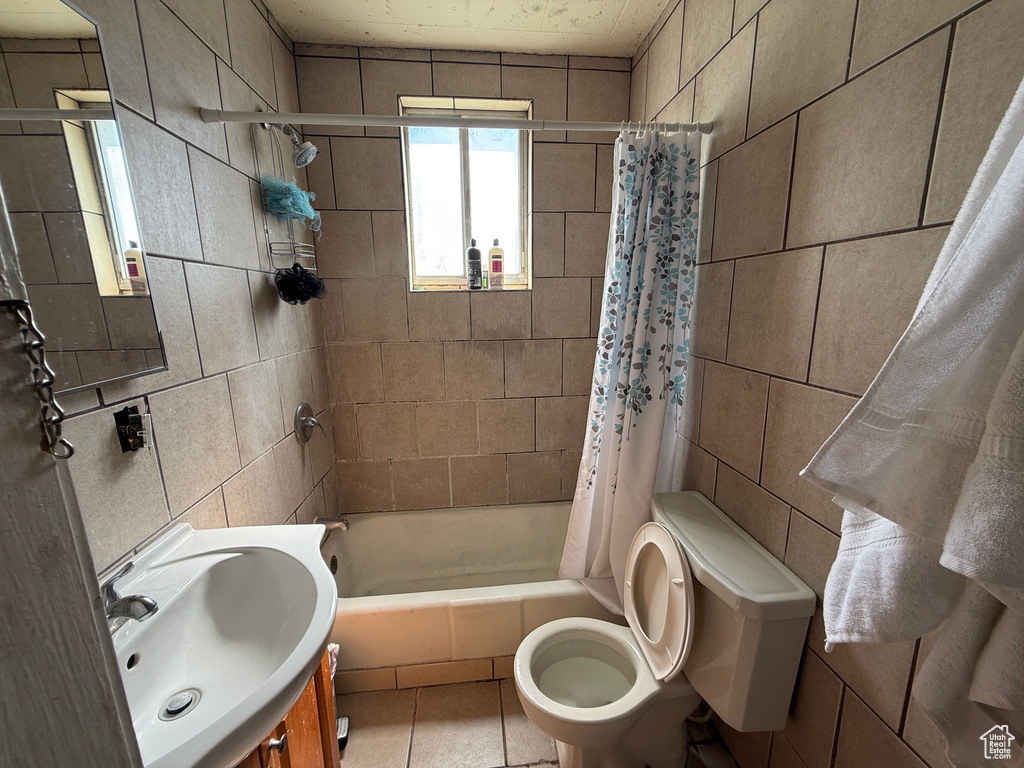 Full bath with tile walls, shower / bathtub combination with curtain, toilet, and vanity